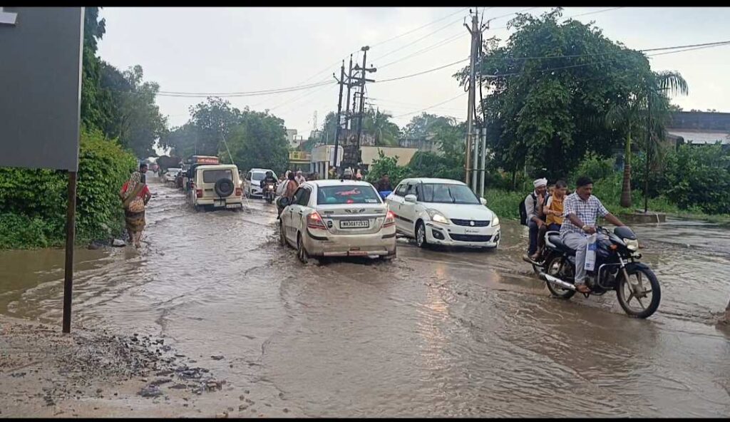 इंदौर इच्छापुर रोड पर बड़वाह में अलका पार्क के पास जलभराव, बाइक और कारें पानी में फंसी हुई
