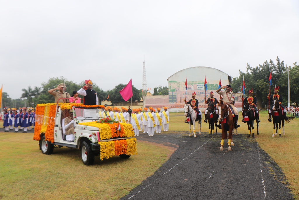 मंत्री विश्वास सारंग द्वारा ध्वजारोहण करते हुए, परेड की सलामी लेते हुए, मंच पर वीरों और कर्मचारियों को सम्मानित करते हुए।”