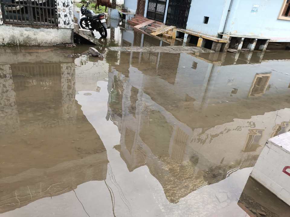 "बड़वाह नर्मदा कॉलोनी में बारिश के बाद जलभराव से भरी सड़क, पैदल यात्रियों और स्कूल जाने वाले बच्चों को हो रही परेशानी।"